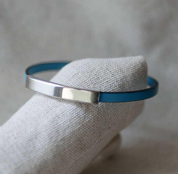 Bracelet simple tour en cuir bleu avec barre métallique argentée.