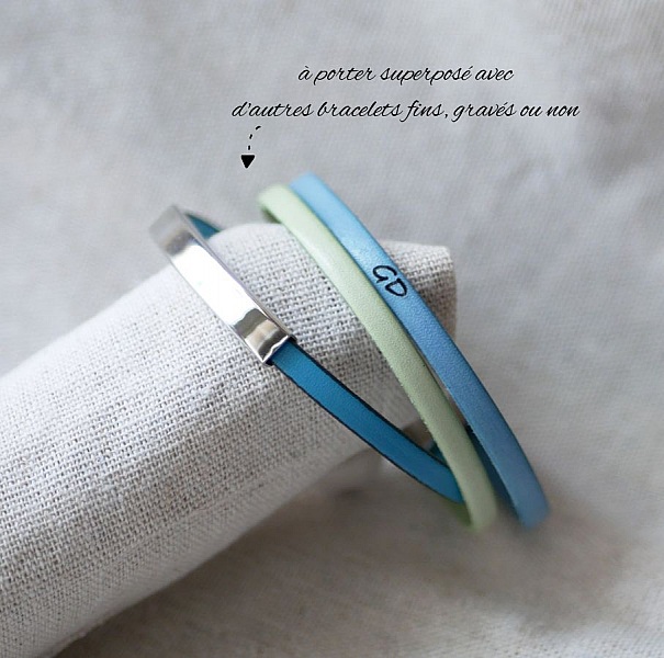 Bracelets fins en cuir avec barre métal superposés.