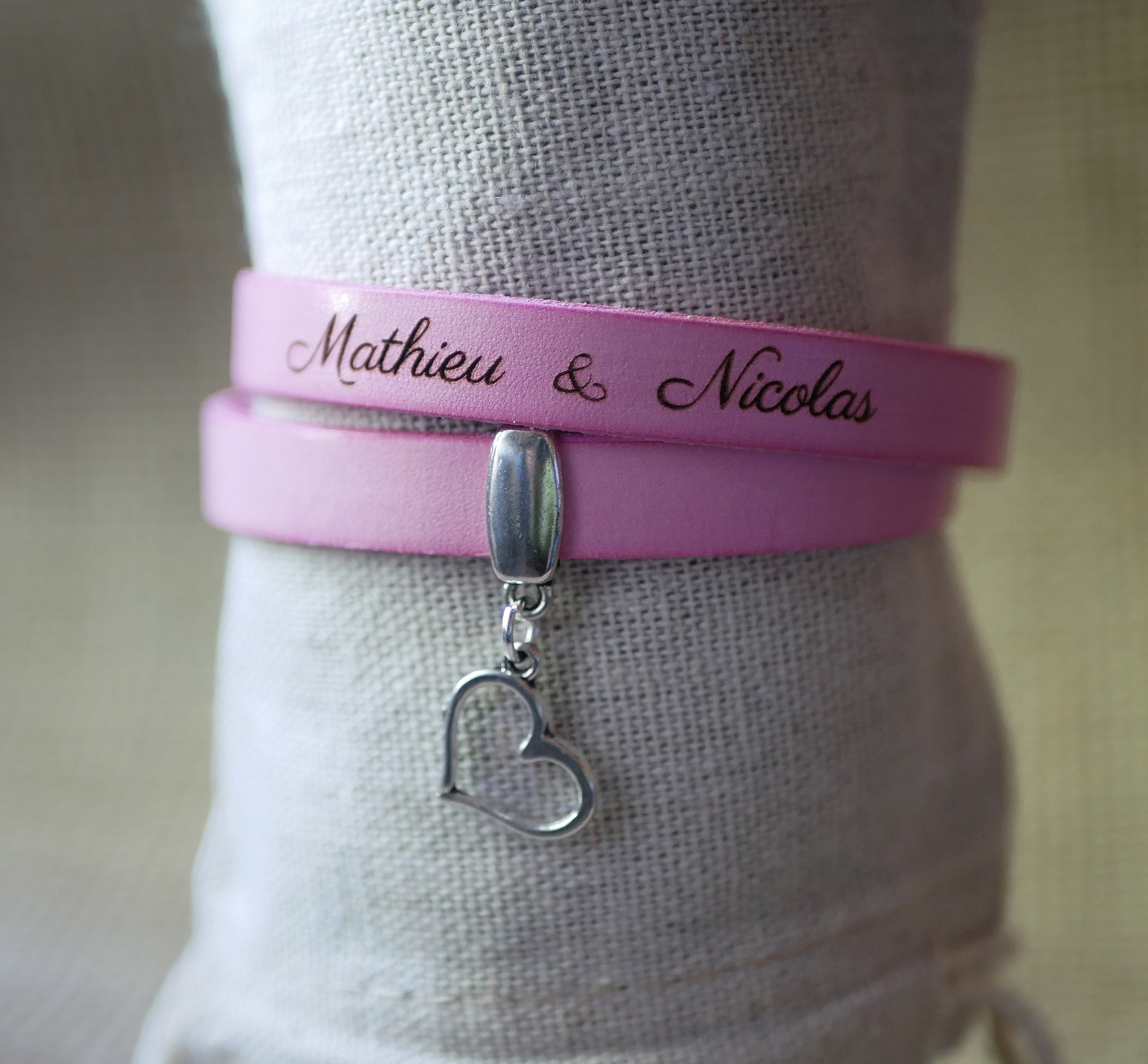 Bracelet double en cuir rose gravé avec pendentif cœur.