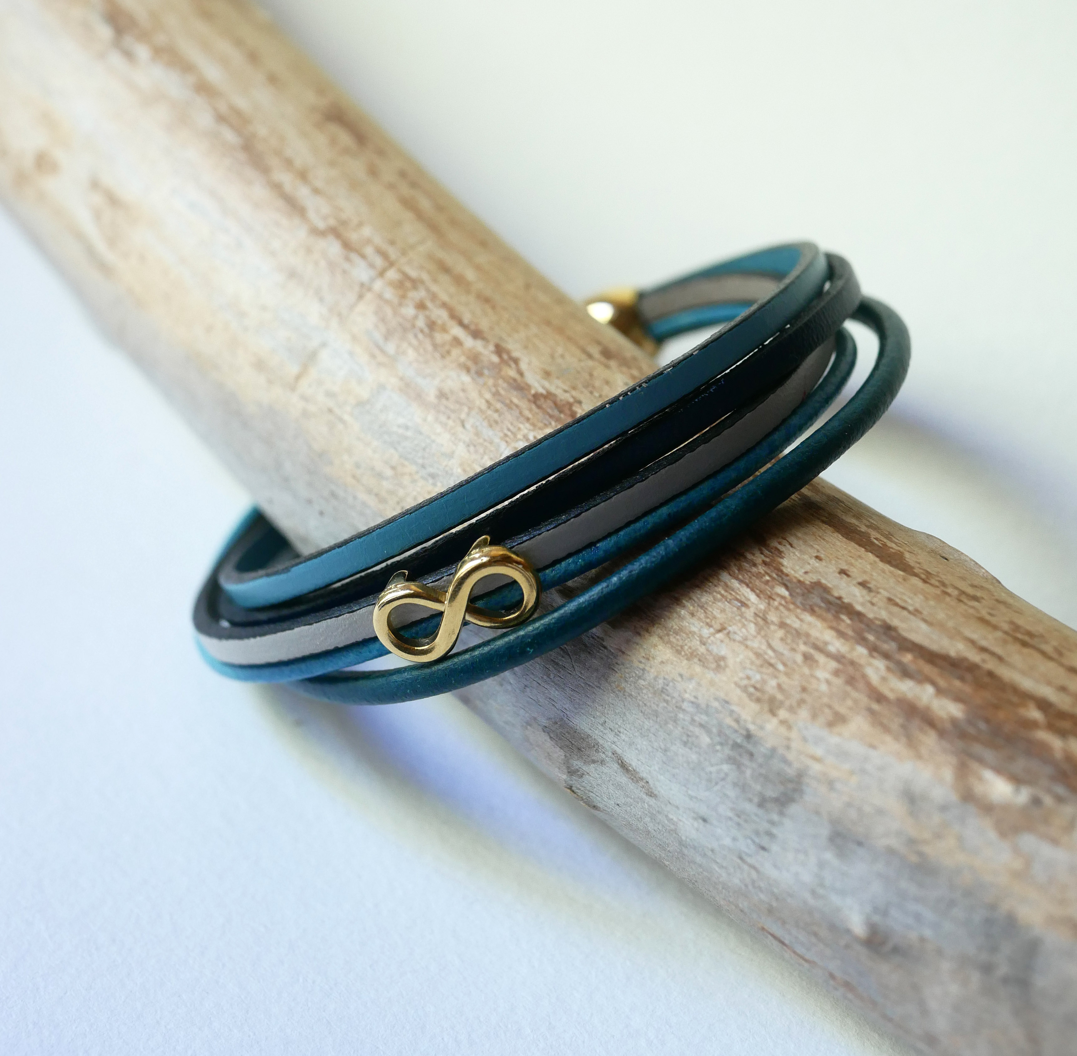 Flerleddet armbånd i blåtonet læder med infinity-motiv i guld
