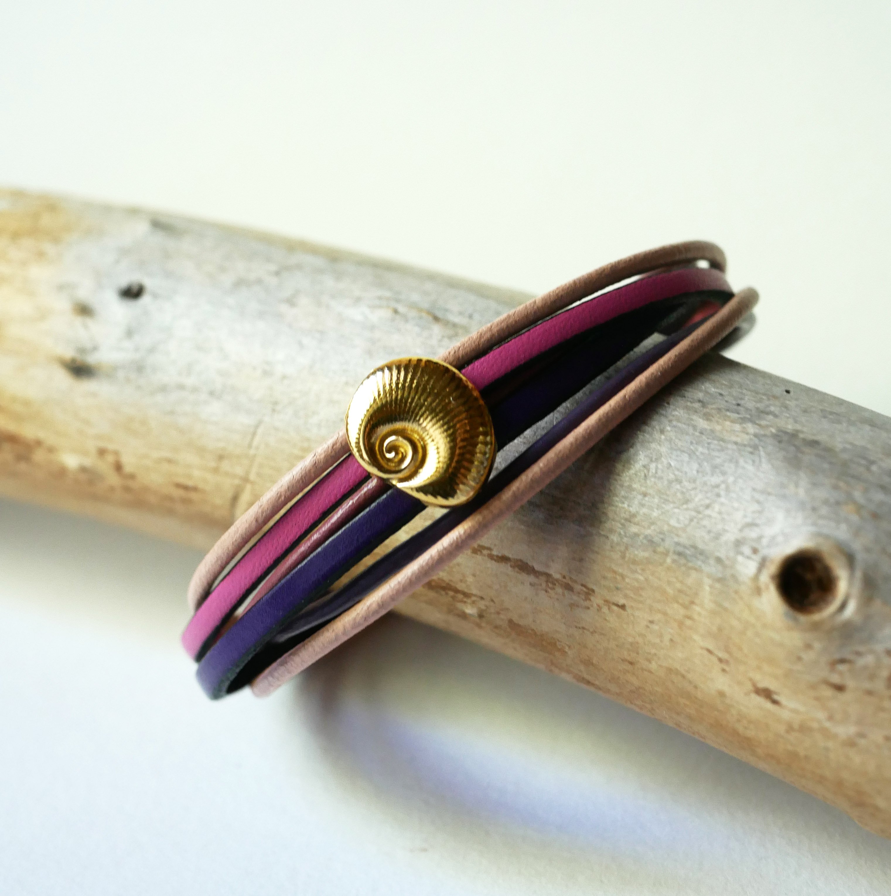 Flerleddet armb&aring;nd i ferskenfarvet og mauvefarvet l&aelig;der med skaldekoration i guld