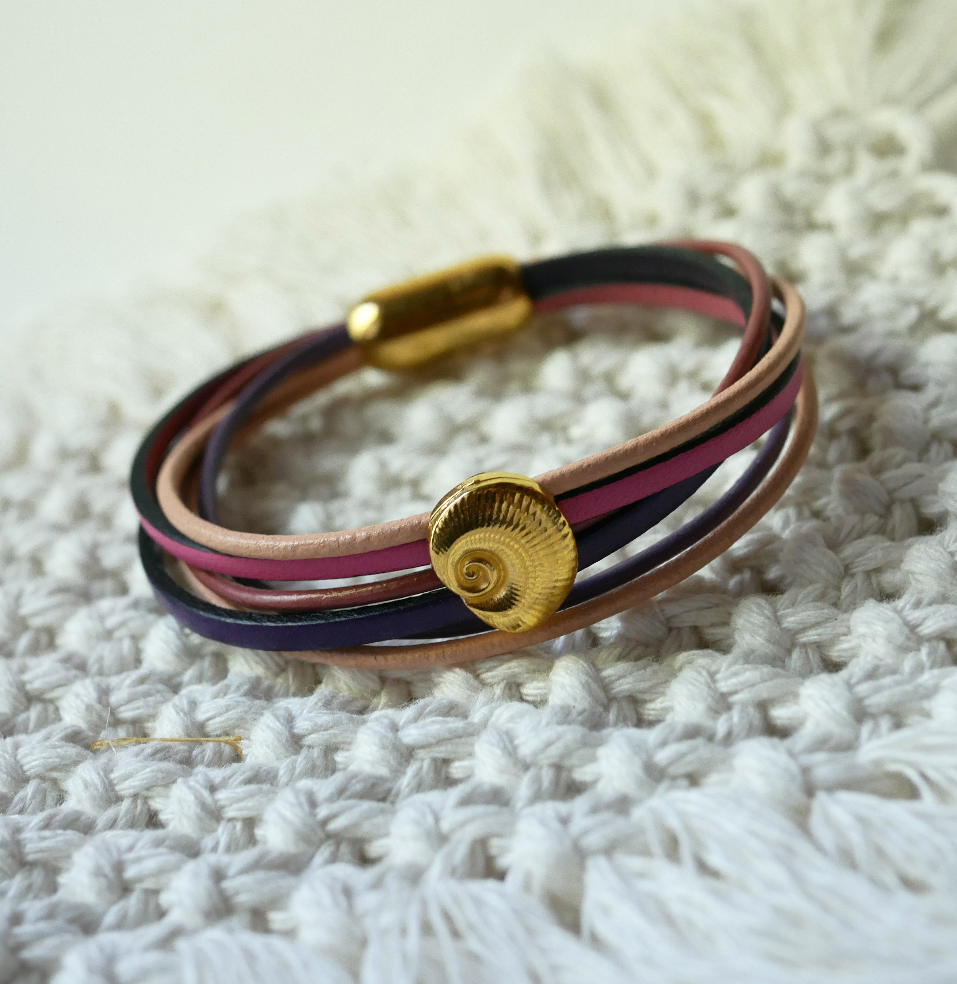 Flerleddet armbånd i ferskenfarvet og mauvefarvet læder med skaldekoration i guld