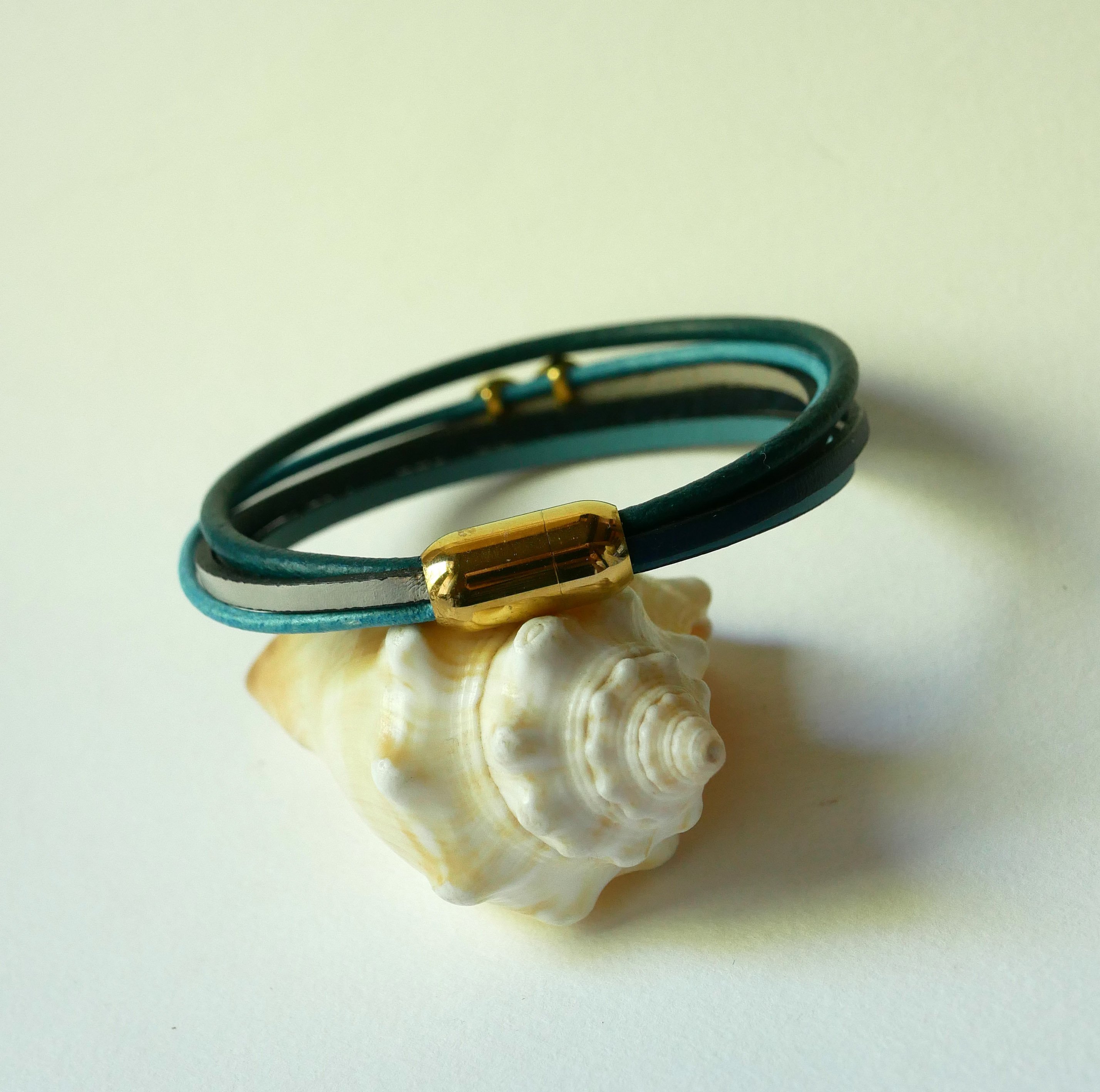 Flerleddet armbånd i blåtonet læder med infinity-motiv i guld