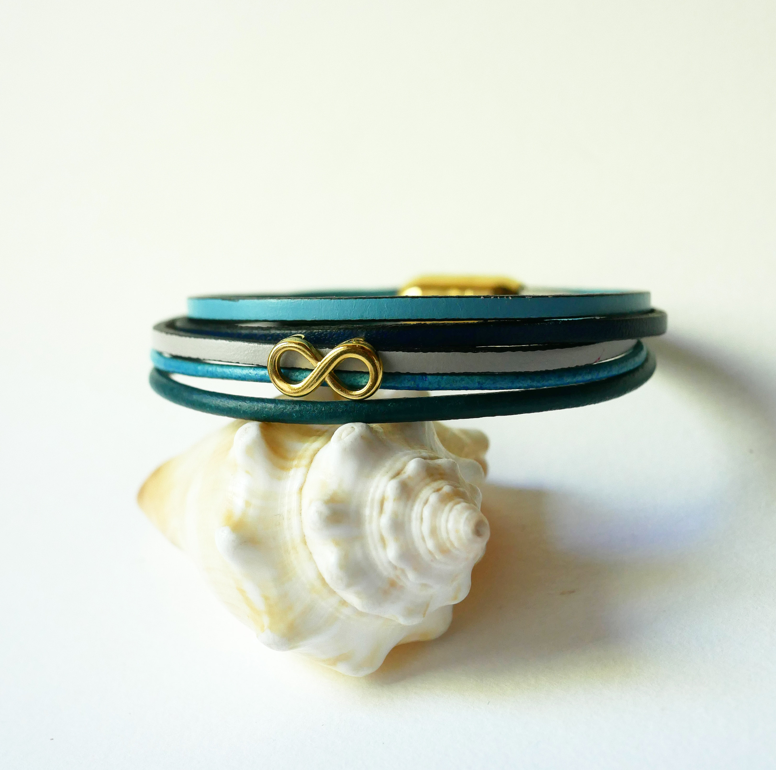 Flerleddet armbånd i blåtonet læder med infinity-motiv i guld