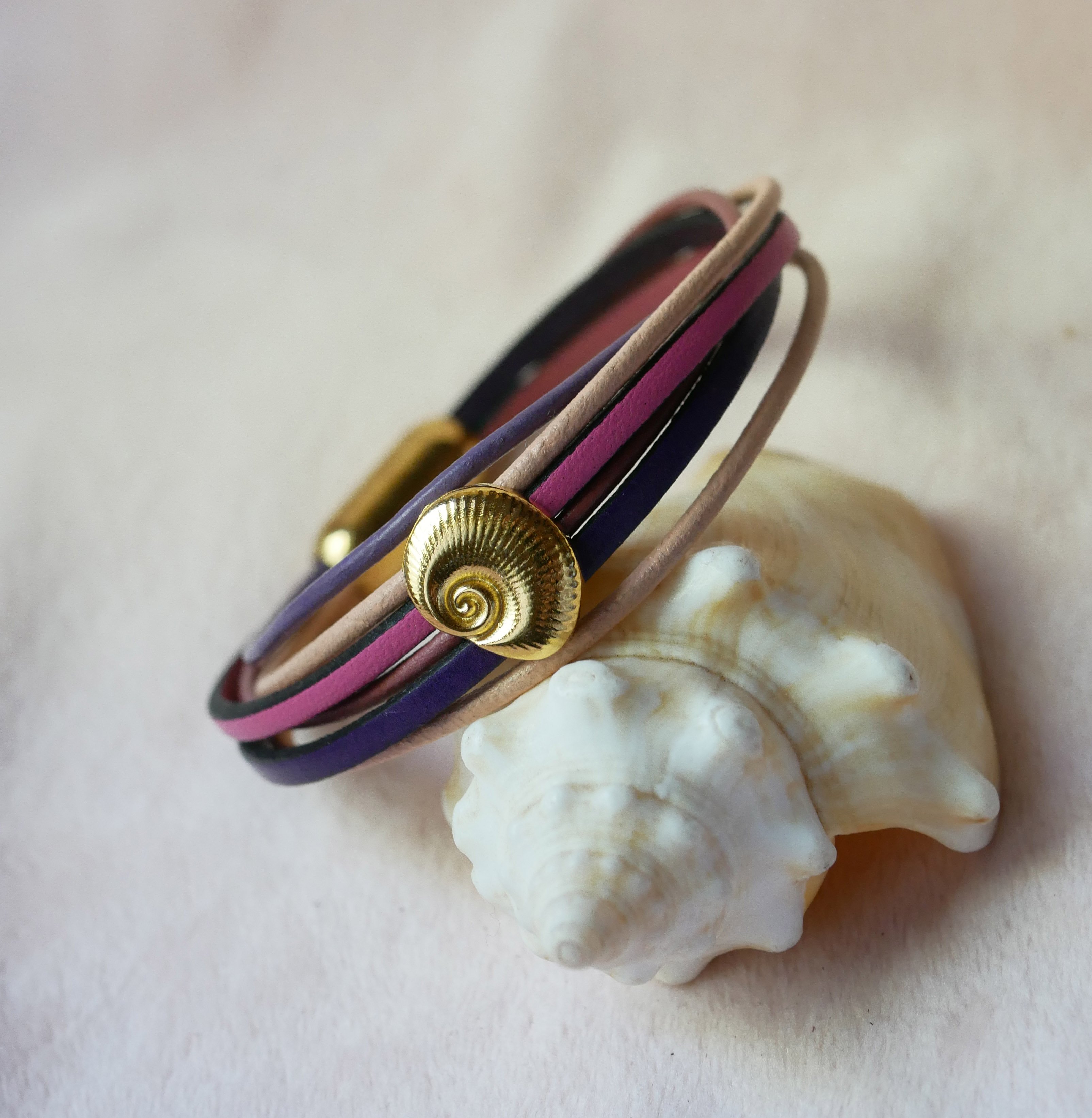 Flerleddet armb&aring;nd i ferskenfarvet og mauvefarvet l&aelig;der med skaldekoration i guld