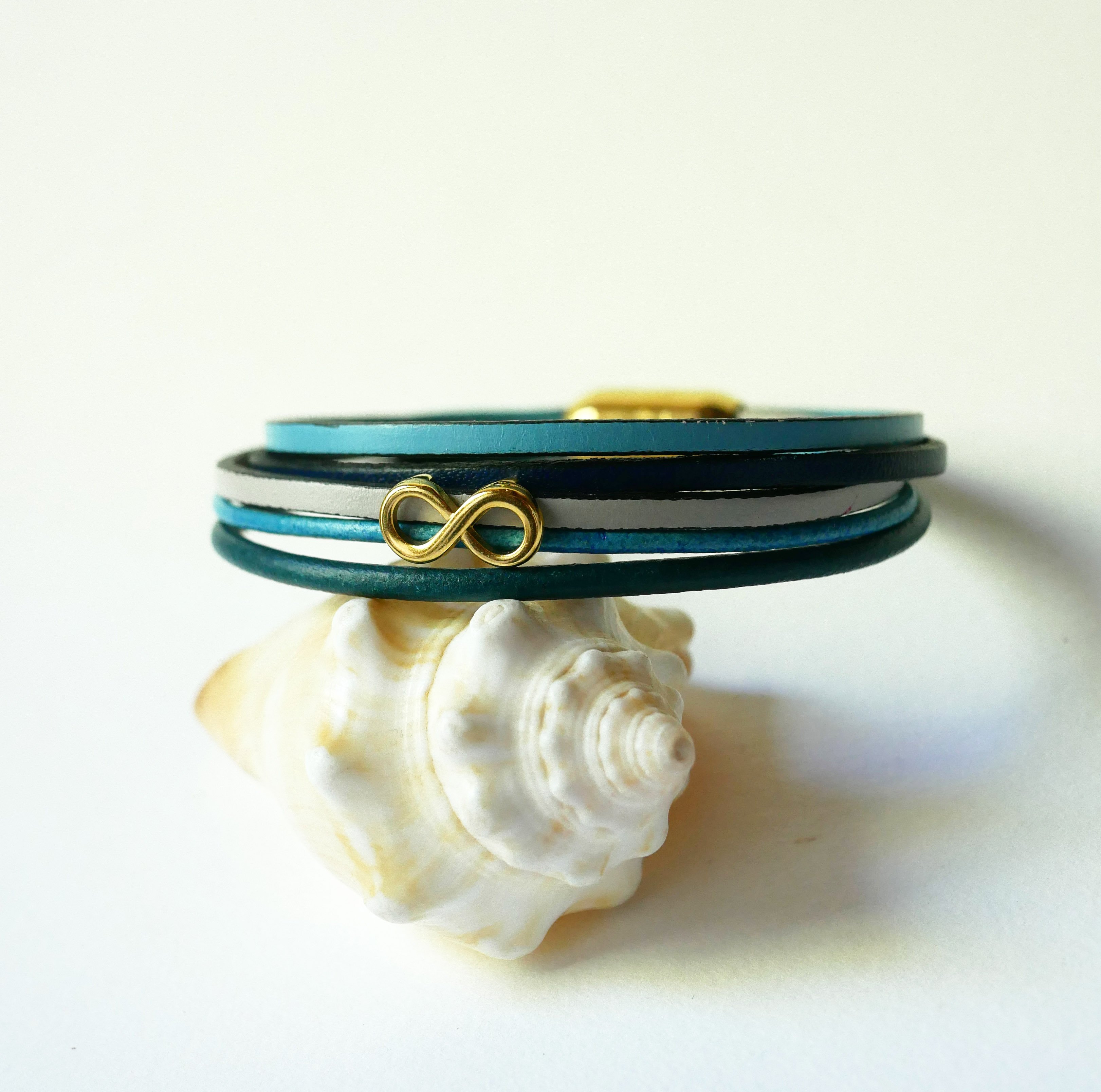 Flerleddet armbånd i blåtonet læder med infinity-motiv i guld