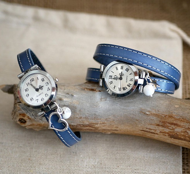 Montres bracelet cuir bleu avec surpiqûres blanches et breloques.