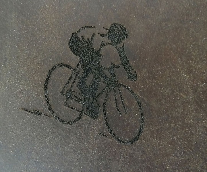 Pochette en cuir café avec gravure de cycliste.