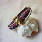 Flerleddet armbånd i ferskenfarvet og mauvefarvet læder med skaldekoration i guld
