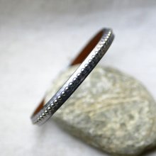 Damearmbånd i mørkegråt metallisk læder med sølvfarvede perler 